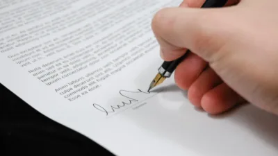 a person's hand holding a pen signing a paper